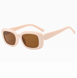 Macro detail of the thick cream rectangular frame and dark lenses of the sunglasses