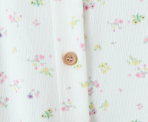 Gros plan sur maille côtelée à imprimé fleuri et détail d'un bouton imitation bois