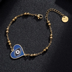 Detail of gold beaded chain bracelet featuring blue heart evil eye pendant in macro view