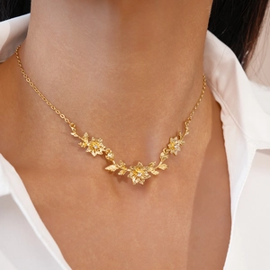 Gros plan d'un collier de fleurs dorées avec cristaux étincelants sur le cou d'une femme