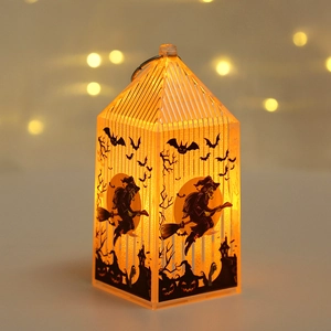 Close-up of glowing orange Halloween lantern with black witch and bat silhouettes