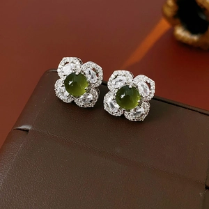 Macro detail of silver flower stud earring with green gemstone and zircon petals