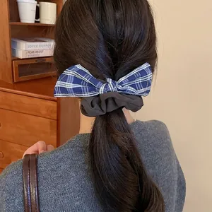 Blue plaid bow and brown scrunchie hair accessory shown on model in a cozy setting