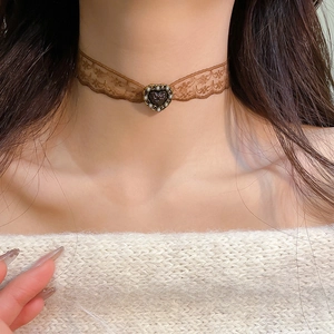 Close-up of vintage brown lace choker featuring a heart-shaped resin pendant with pearl accents