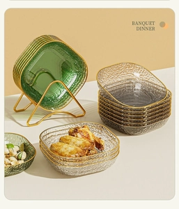 Detail of square glass fruit plates with gold rims and elegant metal storage stand