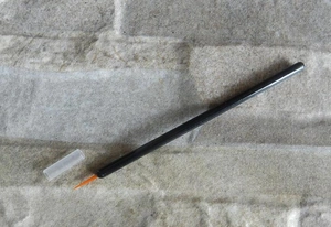Detail of fine tip eyeliner brush with orange bristles and a transparent protective cap
