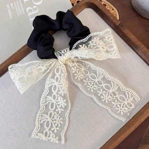 Detail of French vintage black satin scrunchie with cream white lace bow on cloth