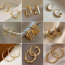 Collection of nine gold earrings including hoops and geometric zircon designs