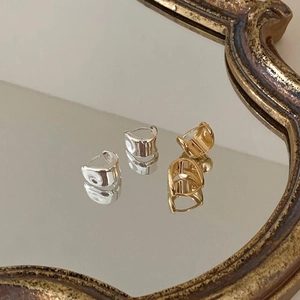 Detail view of gold and silver oval hoop earrings on a vintage mirror with reflections