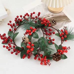 Artificial Christmas pine garland with red berries and pinecones on a white surface