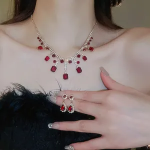 Luxurious red gemstone jewelry set with necklace and earrings on a model with black feathers