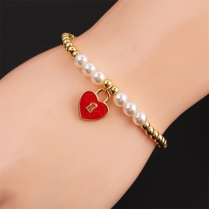 Detail of beaded bracelet with gold beads, white pearls and a red enamel heart lock charm