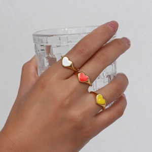 Detailed close-up of three 18k gold plated heart rings with colorful enamel finishes