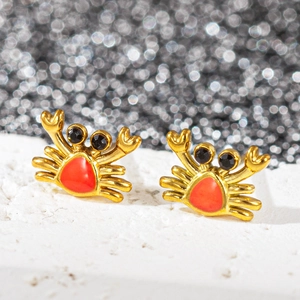 Gros plan de boucles d'oreilles crabe dorées en émail orange et petites gemmes noires