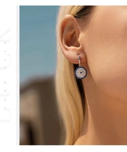 Close-up of S925 sterling silver evil eye drop earring worn on ear in natural light