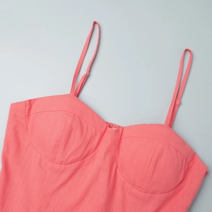 Detail of coral cotton-linen dress featuring bustier cups and fine stitching texture