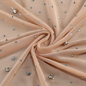 Detail of nude mesh fabric with hand-set crystal rhinestones on elegant evening dress