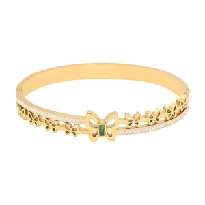 Golden butterfly bangle with green gemstone and sparkling crystals on white background