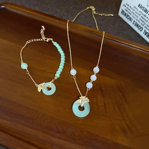 Vue détaillée de l'ensemble collier en feuilles de ginkgo dorées avec jade vert sur bois