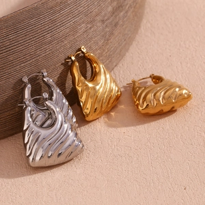 Detailed macro shot of wavy hollow trapezoid earrings in polished gold and silver finish