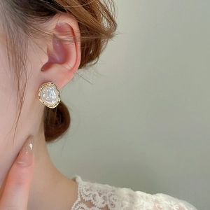 Detail of irregular baroque pearl earrings with gold metal trim worn by model