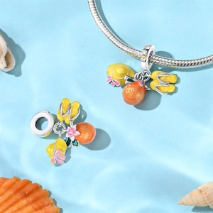 Close-up of silver charms with yellow enamel lemon slices and pink flower on snake chain