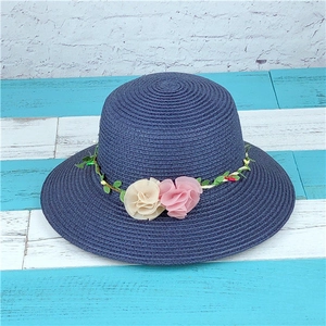Detail of navy straw sun hat with decorative cream and pink floral headband on top