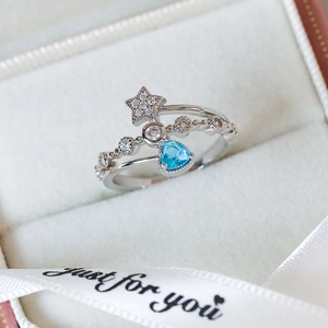 Macro shot of silver ring featuring star and blue heart gemstone in a gift box