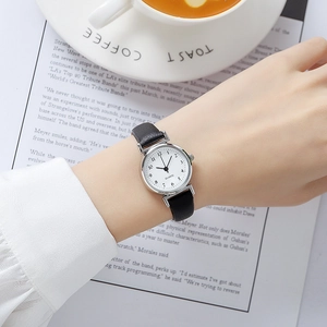 Elegant women quartz watch with black leather strap worn against a minimalist coffee background