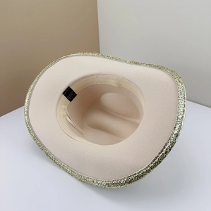 Detail view of cream cowboy hat with gold sequin brim and internal material label