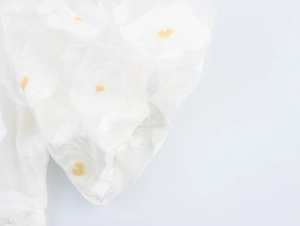 Close-up of intricate 3D floral embroidery on semi-sheer white organza puff sleeve fabric