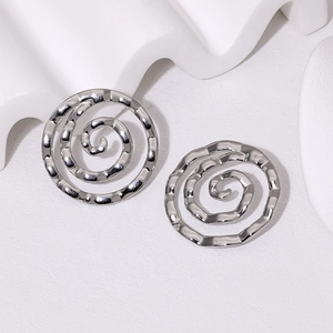 Gros plan de boucles d'oreilles spirales argentées avec texture martelée sur fond blanc