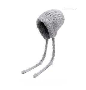Detail of grey plush knit hat with long earflap ties and soft faux fur texture