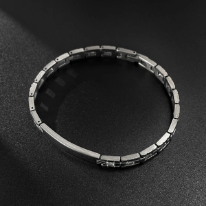 Polished silver stainless steel link bracelet for men on a black textured background