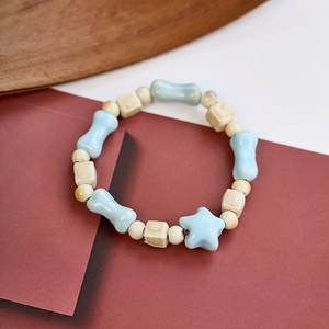 Macro detail of handmade ceramic bracelet with blue bone and star beads on wood surface