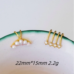 Elegant 14k gold plated pearl ear cuffs with zircon accents on a decorative ceramic edge
