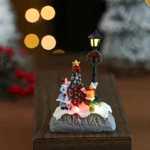 Close-up of glowing resin Christmas miniature house with LED lighting on a wooden desk