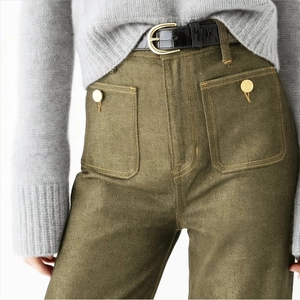 Detail of high-waist olive green metallic pants with front pockets and black belt