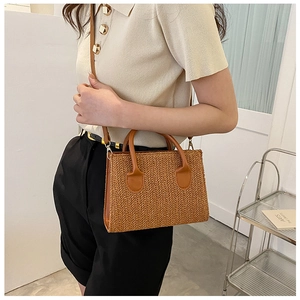 Detailed V-shaped weave pattern on brown straw crossbody bag with faux leather handles