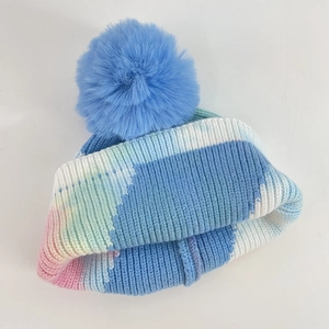 Colorful tie-dye knit beanie with large blue pom-pom for winter warmth and fashion