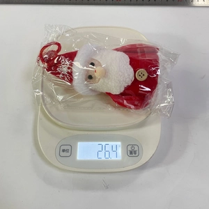 Mesure du poids d'un ornement du Père Noël en peluche affichant 26,4g sur une balance