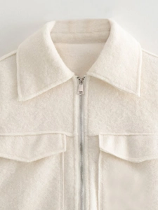 Close-up of beige lapel wool jacket featuring symmetric chest pockets and silver zipper