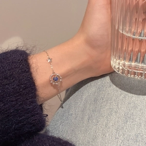 Primer plano de una pulsera con dijes de planeta y estrella en la muñeca en un entorno real