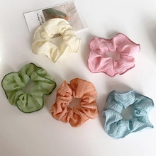 Detail view of five pleated chiffon scrunchies in cream pink green and blue colors