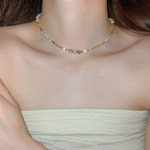 Close-up of a colorful beaded necklace with pearls and gold beads on a model