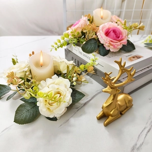Pink and white rose candle holders with a golden reindeer sculpture on a marble table