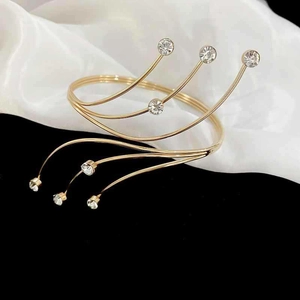 Detailed macro of a gold-plated spiral arm cuff featuring sparkling diamond-cut rhinestones