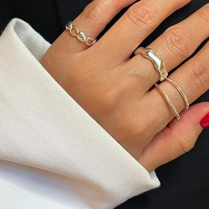 Detail of minimalist 925 sterling silver rings with lava and chain textures on fingers