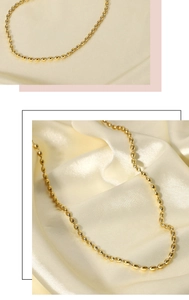 Detailed view of 18K gold plated bead chain necklace on smooth silk background