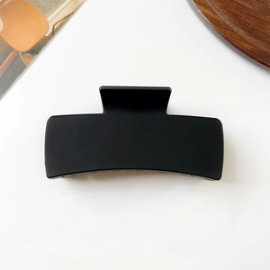 Close-up of a matte black large rectangle hair claw clip on a clean aesthetic background